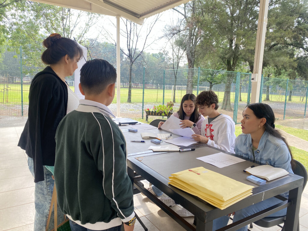 Una alumna entrega su documentación en la mesa de registro de la OMPiT 2025