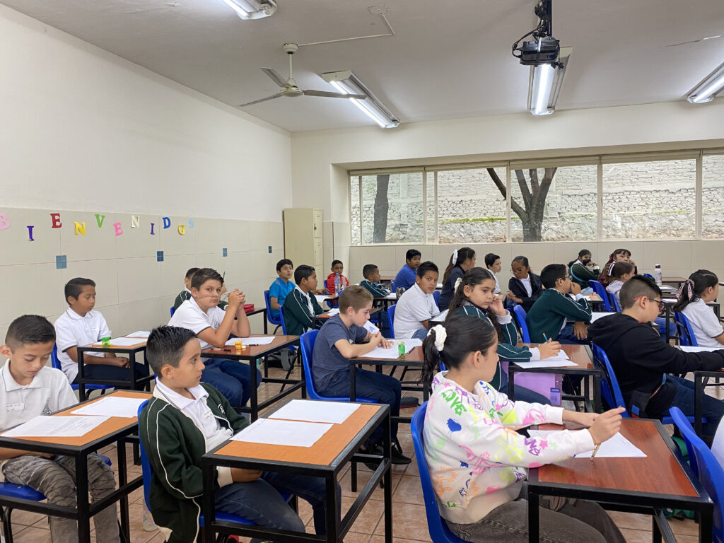 Alumnas y alumnos de primaria resolviendo el examen de la OMPiT en un aula, edición 2025